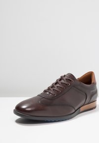 Chaussure en cuir marron à finition lisse, bout arrondi et design à lacets. Dotée d'un talon imitation bois et d'accents de couture subtils.