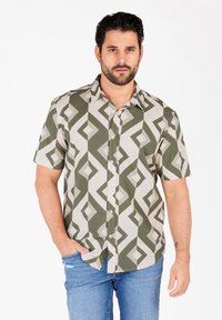 Kurzarmhemd in Grün und Beige mit geometrischen Diamanten- und Streifenmustern. Hergestellt aus strukturiertem Stoff, mit einer Knopfleiste vorne.