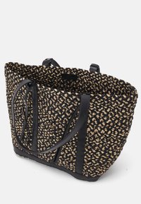 Sac fourre-tout tissé avec un motif noir et beige, des anses robustes en cuir noir, et un design spacieux avec une surface texturée.