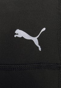 Črn športni material z srebrnim logotipom Puma. Material ima teksturirano površino s šivi ob robovih.