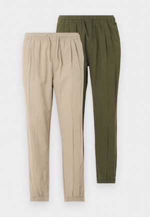 Deux pantalons à taille élastique avec cordon, un beige et un vert olive, avec chevilles resserrées sur fond blanc.