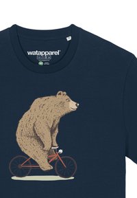 Navyblaues T-Shirt mit einem Grafikdesign, das einen braunen Bären zeigt, der auf einem roten Fahrrad fährt. Das Design weist eine detaillierte Felltextur auf und hat einfache Hintergrundelemente.