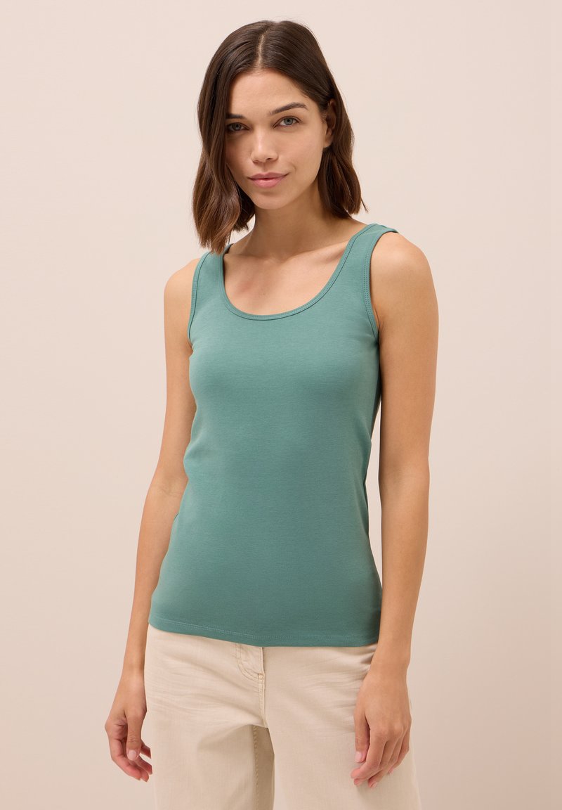 Top aderente color turchese realizzato in cotone morbido ed elastico con scollatura aU. Presenta spalline larghe e una consistenza liscia.