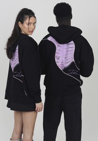 Black hoodies featuring a large purple ribcage graphic on the back. The design includes a smooth texture and embroidered lettering near the hem.