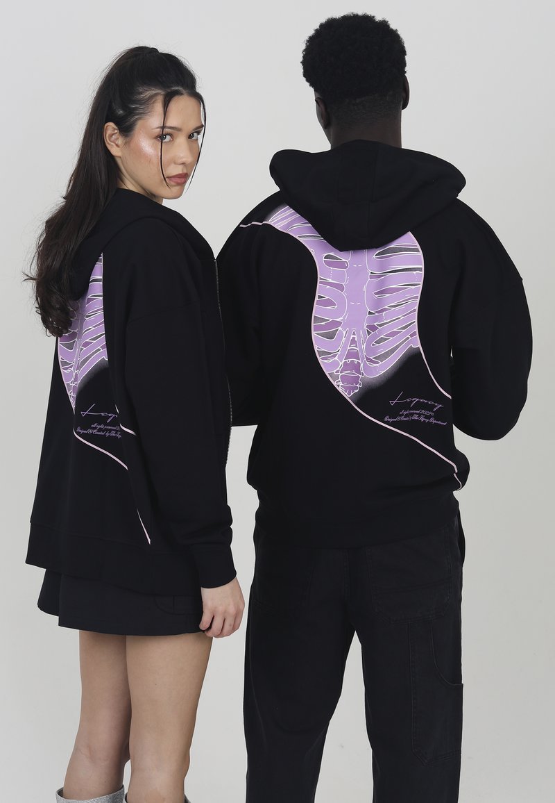 Black hoodies featuring a large purple ribcage graphic on the back. The design includes a smooth texture and embroidered lettering near the hem.