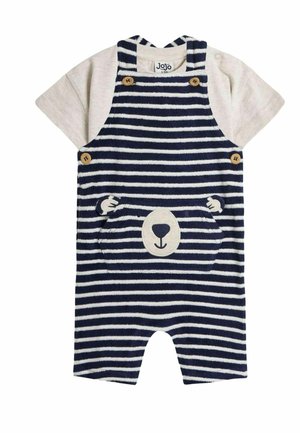 Conjunto de tirantes a rayas en azul marino y crema, con un bolsillo en forma de oso y detalles en botones de madera, combinado con una camiseta de manga corta en un tono beige claro.