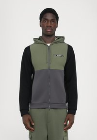 Sweatshirt com capuz e fecho zip em verde oliva, preto e cinza, apresentando um logótipo no peito, com um corte descontraído e textura suave.