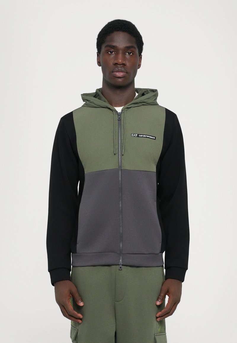 Sweatshirt com capuz e fecho zip em verde oliva, preto e cinza, apresentando um logótipo no peito, com um corte descontraído e textura suave.