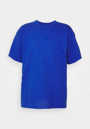 Kék pamut póló kerek nyakkivágással és rövid ujjakkal. Apró hímzett Nike embléma található a mellrészen. Sima textúra.