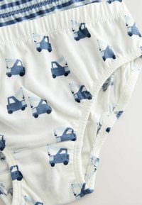 Culotte en tissu blanc ornée d'un motif répété de camions bleu clair et bleu foncé. Taille élastique avec des rayures horizontales dans des teintes de bleu.