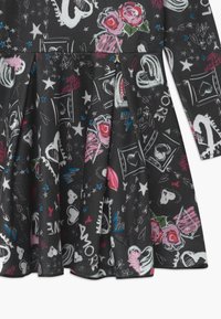 Schwarzer Stoff mit verstreuteten weißen Herzen, Sternen, rosa Rosen und blauen Blitzen, mit Worten wie "Amore" und "Liebe" im Graffiti-Stil.