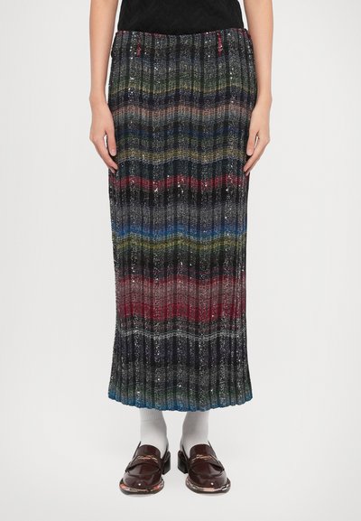 Knælang plisseret nederdel med multicolor horisontale striber, med glitrende tråde; parret med brune loafers og hvide sokker.