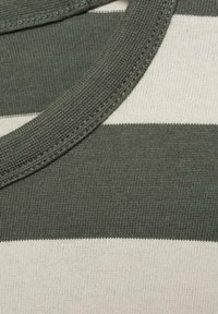 Nahaufnahme eines grün-weiß gestreiften Strickkragens, die Textur des Stoffes und die Nähdetails zeigend.