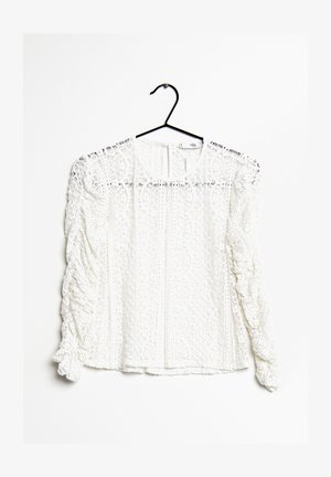 Blusa bianca in pizzo con scollatura rotonda, maniche lunghe arricciate e intricati motivi floreali. Presenta un gancio per appendere.