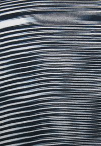 Textil que presenta rayas horizontales de azul marino, azul claro y blanco, creando un patrón dinámico. Textura de punto suave visible.