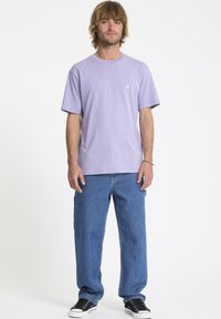 Lavendel bomulds t-shirt med rund hals, parret med blå denim jeans og sorte sneakers. Enkel design med minimal branding.