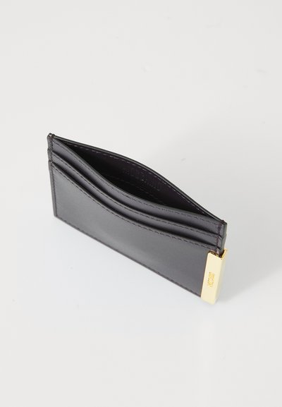 Portofel din piele neagră pentru carduri, cu trei sloturi, textură netedă, design elegant și un accent metalic auriu la un capăt, pentru un detaliu suplimentar.