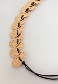 Bronzekette mit ovalen, gehämmerten Scheiben, die durch einen schwarzen Kordel verbunden sind. Jede Scheibe hat eine strukturierte Oberfläche und einen kleinen schwarzen Akzent.