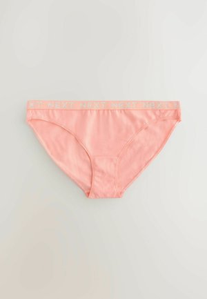 Vaaleanpunaiset puuvillaiset alushousut, joissa on sileä pinta ja leveä elastinen vyötärönauha, jossa lukee valkoisilla kirjaimilla "NEXT".