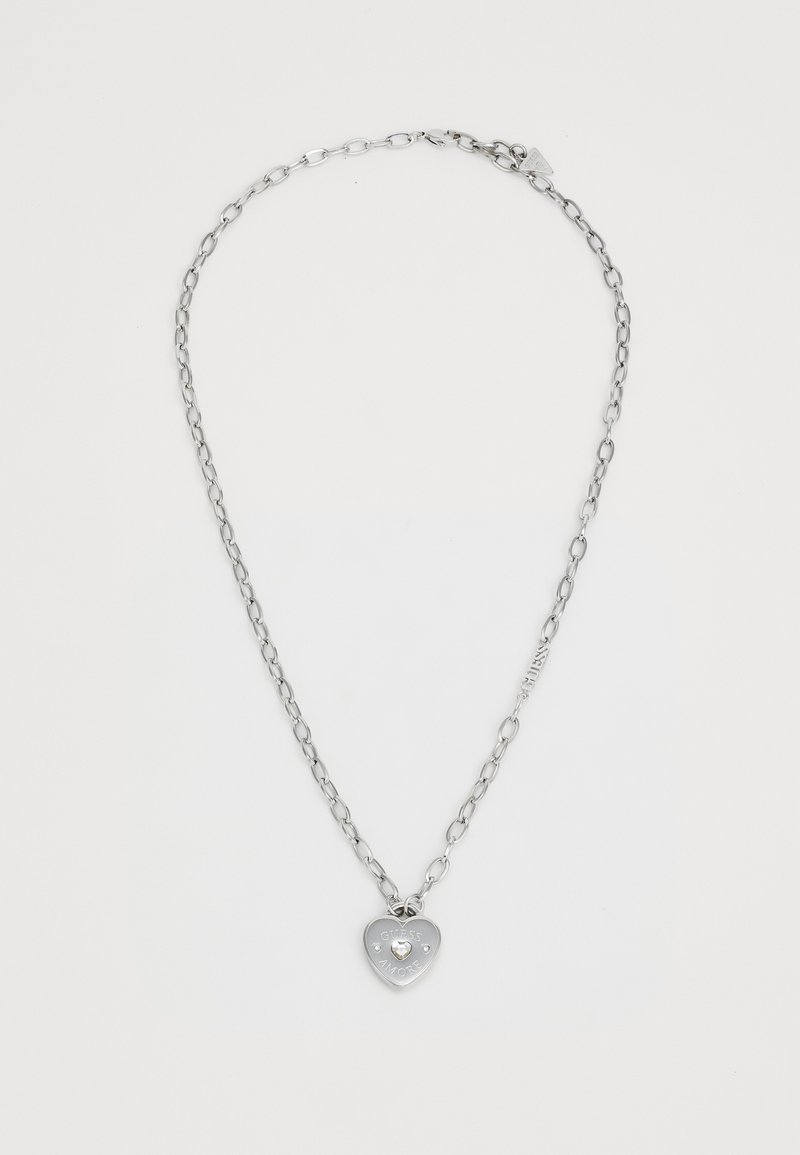 Silver metal necklace with linked chain, featuring a heart-shaped pendant engraved with "GUEST AMORE" and two clear stones.