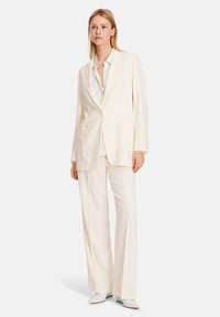 Cream-colored suit consisting of a blazer with a single button and matching wide-leg trousers, made from smooth fabric with a tailored fit.