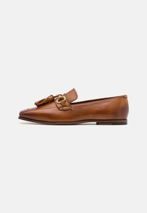 Brun læderloafer med dusk og guldbeslag, flad sål og spids tå, vist fra siden mod hvid baggrund.