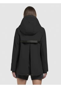 Zwarte waterdichte jas met capuchon, een rugventilatieopening met een logo-band, en lange mouwen. Het materiaal lijkt glad met een matte afwerking.