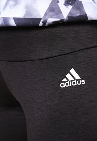 Leggings sportivi neri realizzati in un tessuto testurizzato, con il logo bianco di Adidas sulla fascia in vita.