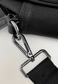 Black leather bag strap with a glossy silver metal clip and textured fabric. Features a robust hook attachment for secure fastening.