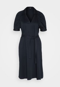 Robe midi noire avec col en V, manches courtes bouffantes, col et ceinture en tissu nouée à la taille sur fond blanc.