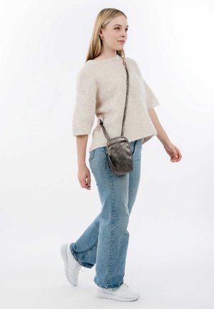 Crossbody bag in metallic grey leather; rectangular shape with zip closure and tassel detail; worn with a cream sweater and blue jeans.