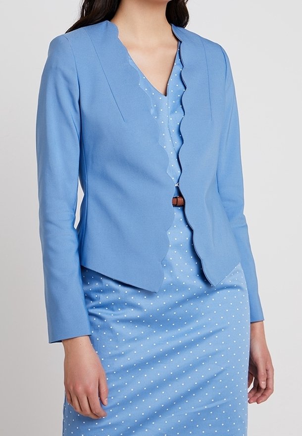 Light blue blazer with scalloped neckline and long sleeves, paired with a light blue polka dot dress, featuring a cinched waist.