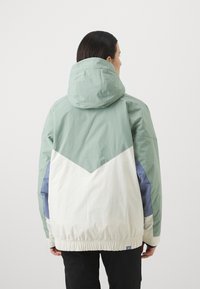 Veste légère à capuche avec un design coloré en blocs de couleurs mint, blanche et bleu pâle. Ourlet élastique et texture lisse.
