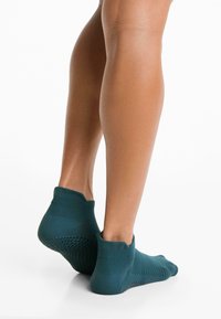 Türkiz ankle zoknik, bordázott dizájnnal és hálós betétekkel a légáteresztésért, amelyek szoros illeszkedést biztosítanak a sarok és a lábujjak körül.