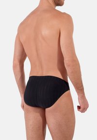 Caleçons de bain noirs avec une texture côtelée, dotés d'une taille haute et d'une coupe ajustée, adaptés pour la natation et les activités sportives.