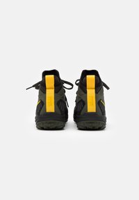 Scarpe da trekking in verde scuro e nero, con un tallone giallo, colletto imbottito e suola in gomma testurizzata con motivi antiscivolo.