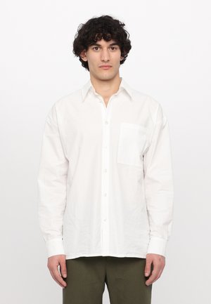 Chemise blanche à boutons, en coton, avec un col pointu, des manches longues et une poche plaquée sur la poitrine gauche.