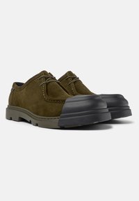 Scarpe in camoscio di colore verde oliva con punta in gomma, cuciture a contrasto e design arrotondato. Suola spessa e testurizzata per maggiore aderenza e durata.