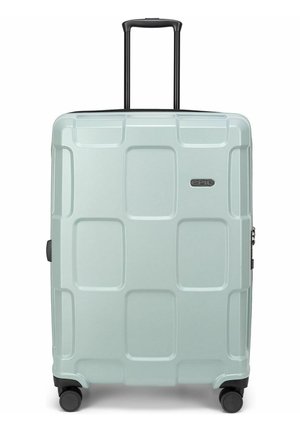 Valise rigide bleu clair avec poignée télescopique, quatre roues noires pivotantes et motif carré embossé sur la surface avant.