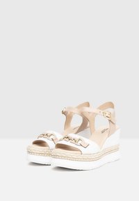 Sandali con zeppa caratterizzati da una tomaia in pelle bianca con una cinghia beige, fibbia dorata e zeppa in juta intrecciata; suola in gomma texture per una buona aderenza.