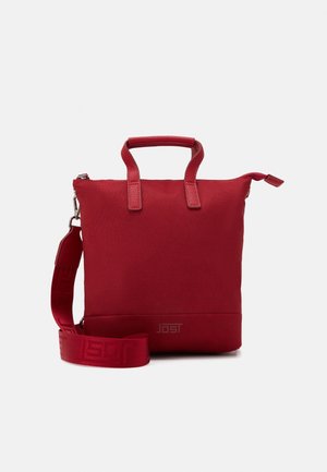 Sac bandoulière carré rouge avec poignées supérieures, bandoulière amovible, fermeture éclair et logo de marque discret en bas à l'avant.