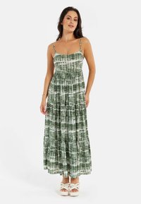 Green and white tiered maxi dress with spaghetti straps, featuring a tie-dye pattern and a relaxed fit, made from soft fabric.
