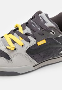 Gray and black sneaker with yellow laces. Features suede and textile materials, perforated accents, and a padded collar for comfort.