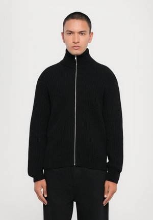 Black ribbed knit zip-up sweater with a high collar and long sleeves. Features a silver zipper, relaxed fit, and textured fabric.