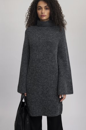 Kulsorte grå sweaterkjole med høj krave, brede ærmer, blød tekstur og oversized pasform, parret med en sort taske.
