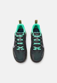 Zwarte sportschoenen met een bovenwerk van mesh, voorzien van een groene voering, veters en accenten. Inclusief een trekband en een gestructureerde zool.