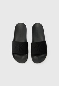 Black slide sandals featuring a smooth synthetic footbed and a thick fabric strap embossed with "CK." Flat design with rounded edges.
