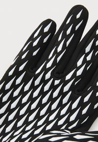 Gants noirs avec une prise texturée présentant un motif en diamant blanc. Fabriqués en matériau flexible, conçus pour une dextérité et une traction améliorées.