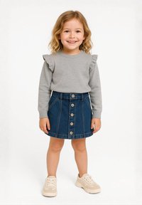 Hall grey sweatshirt, milledega varrukad, koos sinise teksaseeliku ja eesnuppudega. Laps kannab beeže tossusid.