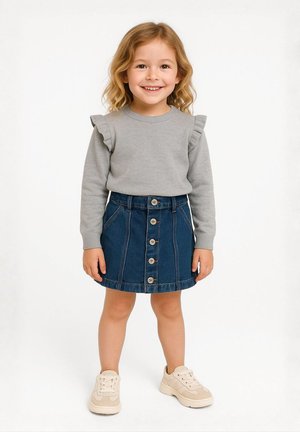 Sivi dukserica s volanastim rukavima, u kombinaciji s plavom traper suknjom s prednjim dugmadi. Dijete nosi bež tenisice.